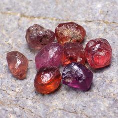 some very pretty colored rocks on a stone surface with one rock in the foreground