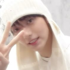 a young man wearing a white hat making the peace sign