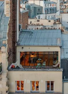 an apartment building with lots of windows on top of it's roof and some buildings in the background