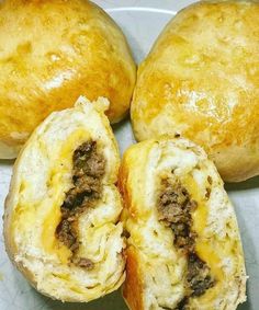 three rolls with cheese and meat inside on a plate