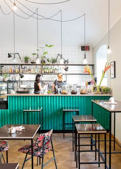 the interior of a restaurant with green walls and wooden tables, two people sitting at their desks