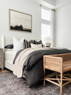 a bed with black and white pillows on top of it next to a wooden table