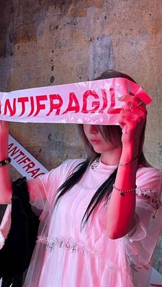 a woman holding up a scarf with the word antifragil written on it in front of her head