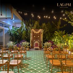 an indoor ceremony setup with wooden chairs and greenery on the walls, decorated with lights