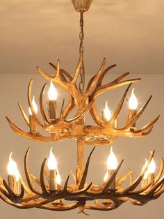 a chandelier with deer antlers hanging from it's sides and lit candles in the middle