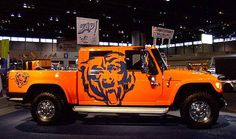 an orange truck with a bear painted on it's side in a showroom