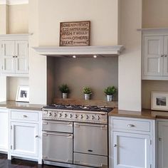 a large kitchen with white cabinets and an old fashioned stove top oven in the center