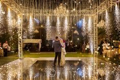 a bride and groom are standing in front of an outdoor wedding venue with chandeliers