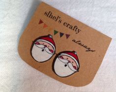 a pair of santa claus earrings on top of a piece of paper