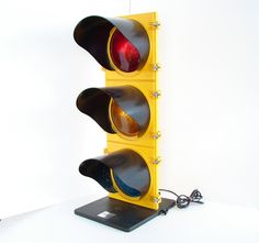 two traffic lights are sitting next to each other on a white surface, one is red and the other is yellow