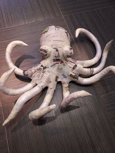 an octopus made out of newspaper strips on the floor with it's legs curled up