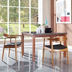 a dining room table with two chairs and a vase on the table next to it