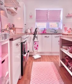 a pink and white kitchen with an ironing board on the floor in front of the stove