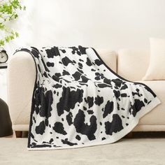 a black and white cow print blanket sitting on top of a couch next to a lamp