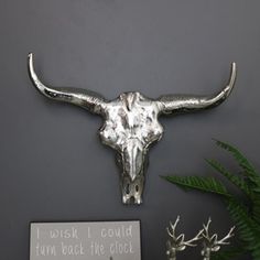 a cow's head is mounted on the wall next to a plant and sign