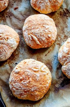 some bread rolls are sitting on a piece of wax paper and ready to be baked