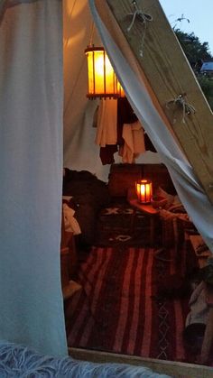 a tent with some lights in it next to a bed and pillows on the floor