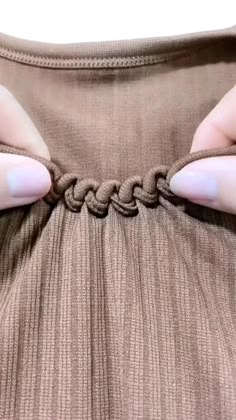 a woman's hands are pulling on a piece of fabric that has been knoted together