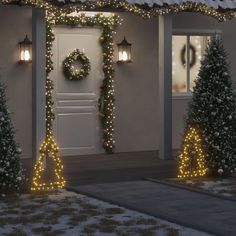 christmas lights decorate the front of a house with trees and wreaths on either side