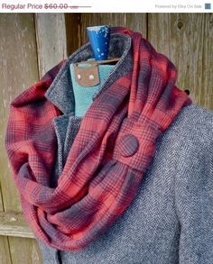 a red and gray plaid scarf hanging on a coat rack with a cup in it