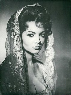 an old black and white photo of a woman wearing a shawl over her head