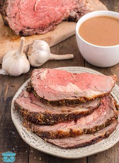 sliced roast beef on a plate next to garlic and a cup of hot chocolate sauce