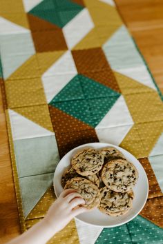 a person reaching for some cookies on a plate