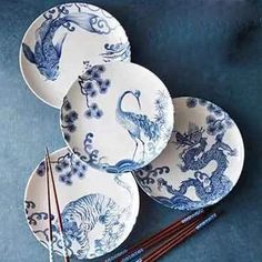 four blue and white plates with chopsticks next to each other