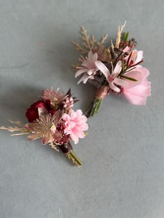 two pink and red flowers sitting next to each other on top of a gray surface