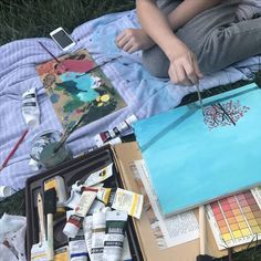 a person sitting on the ground with some art supplies