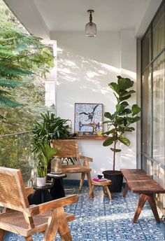 an outdoor patio with wooden chairs and potted plants on the side wall, next to a blue tiled floor