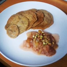 a white plate topped with three cookies and some food on top of a wooden table