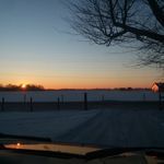 the sun is setting over a frozen lake