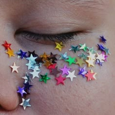 a close up of a person's face with multicolored stars on their cheek