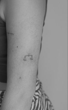 a woman's arm with a tattoo on it that has an image of a balance scale