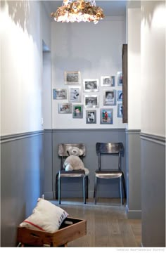 two chairs in a room with pictures on the wall and a light fixture hanging from the ceiling