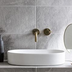 a white sink sitting on top of a counter next to a mirror and vases