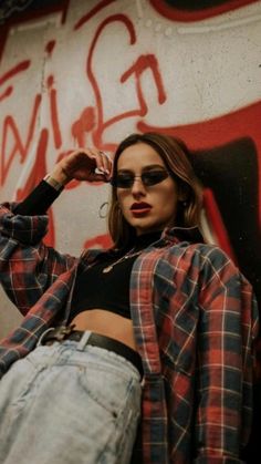 a young woman leaning against a wall with graffiti on it