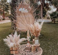 a chair with feathers on it sitting in the grass next to some baskets and vases