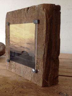 a wooden frame sitting on top of a table next to a rock and a potted plant