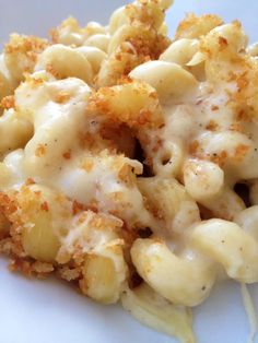 a white plate topped with macaroni and cheese covered in grated cheese sauce