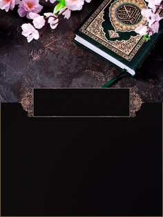 an open book on a table next to pink flowers and a gold frame around it