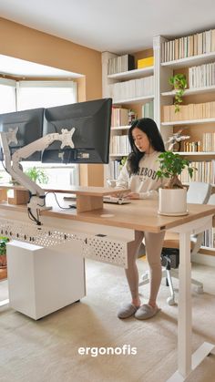 a woman sitting at a desk in front of a computer monitor and bookshelf