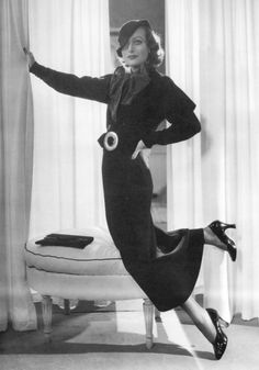 a black and white photo of a woman leaning against a curtain