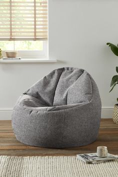 a bean bag chair sitting on top of a wooden floor next to a potted plant