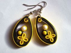 a pair of yellow and black earrings with beads on them sitting on a white surface