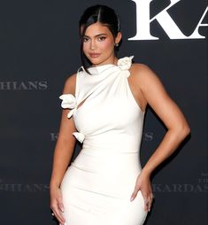 a woman in a white dress standing on a red carpet with her hands on her hips