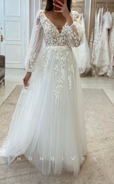 a woman taking a selfie in her wedding dress while wearing a long sleeved gown