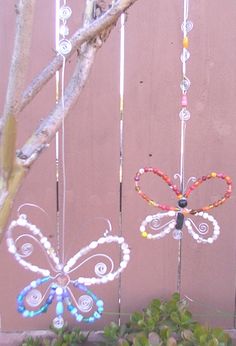 three wind chimes hanging from a tree in front of a wooden fence with leaves