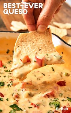 a tortilla chip being dipped with cheese sauce